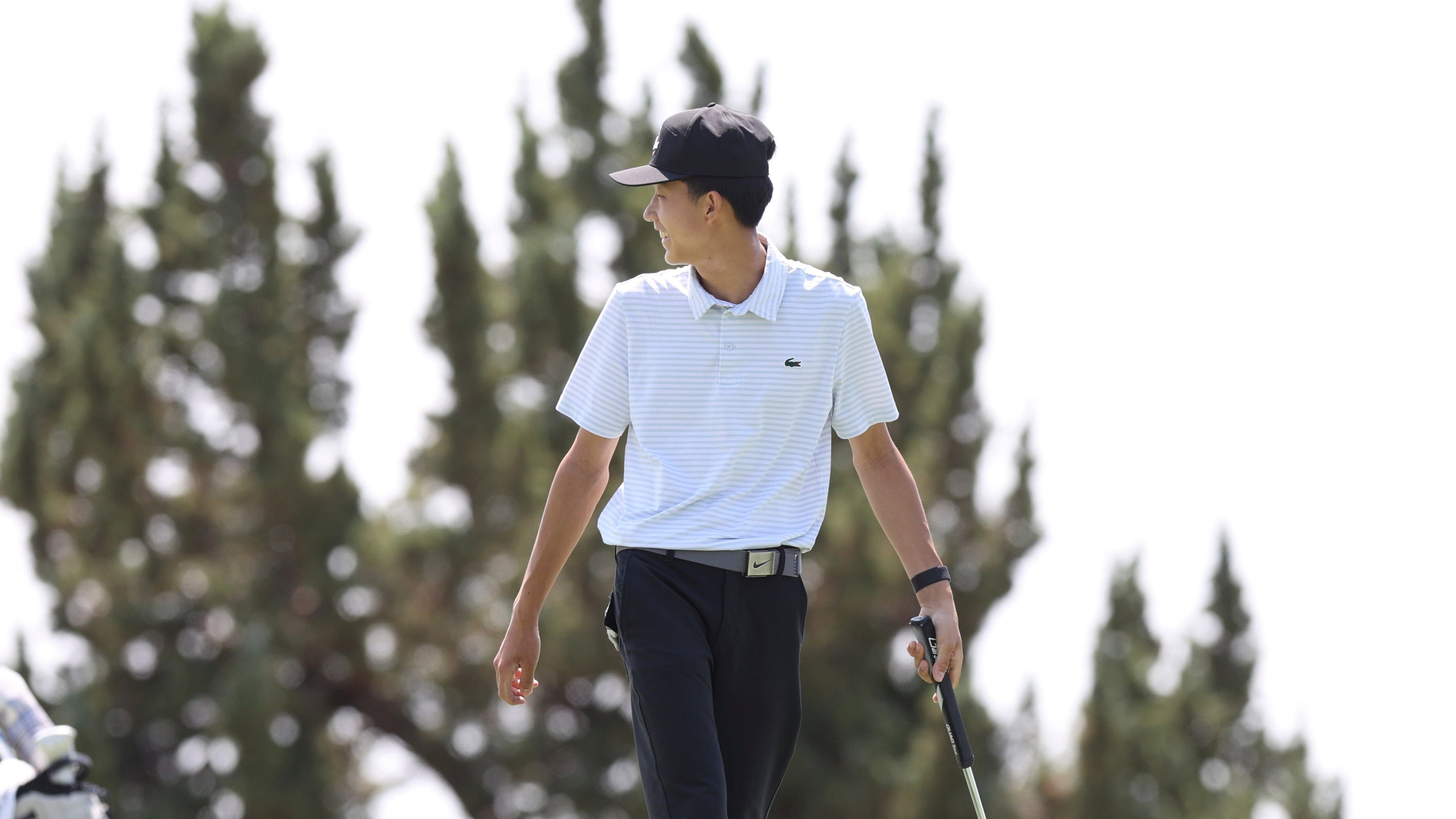Benny 
walking on a golf course with trees in the background